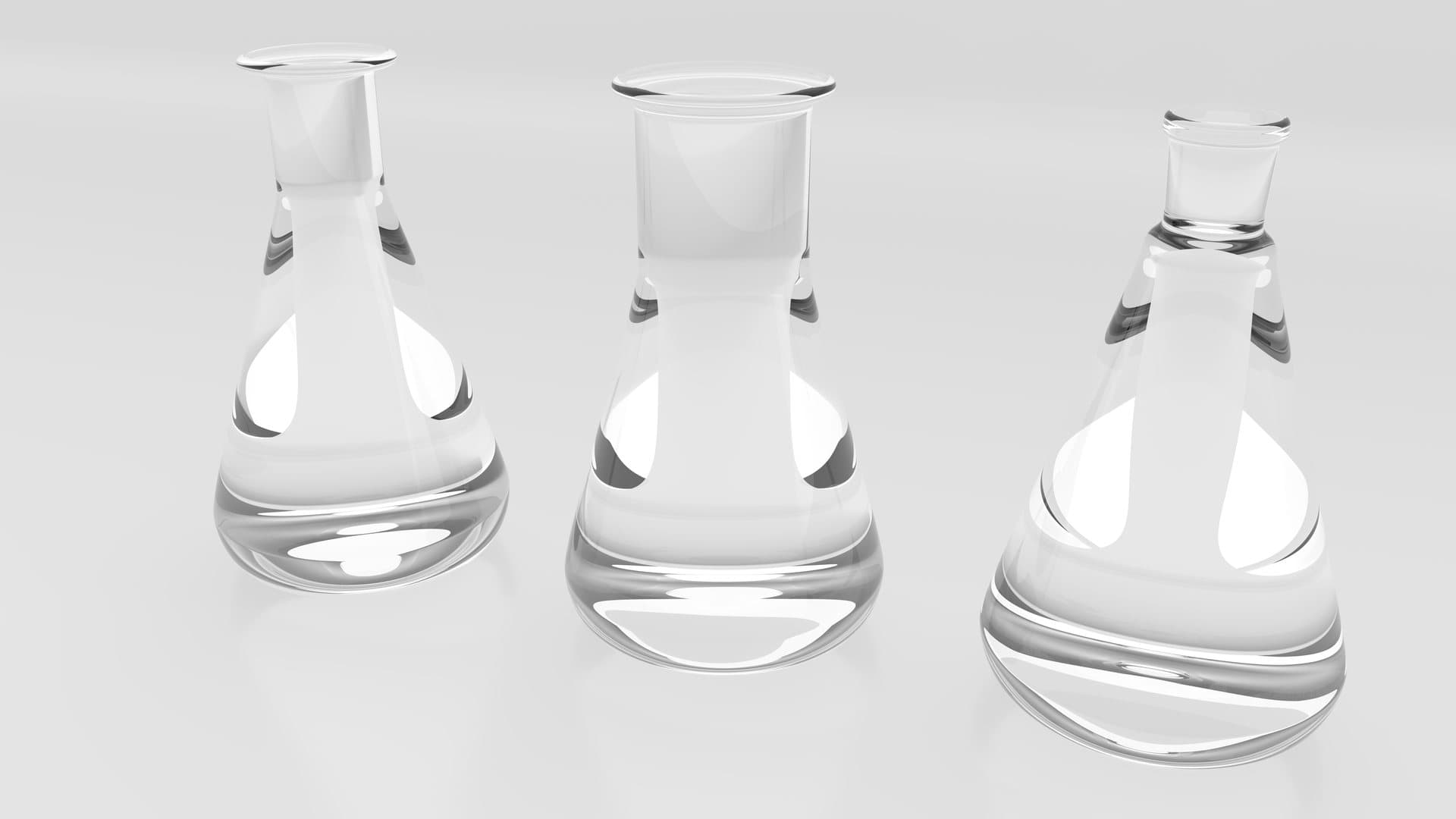 Three clear glass conical flasks on a white surface